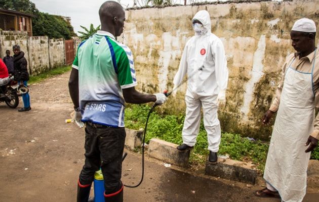 A health worker being disinfected after treating a patient in Freetown, Sierra Leone. / Michael Duff.,Ebola