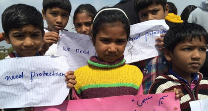 Children holding 'we need protection' signs. / BBC