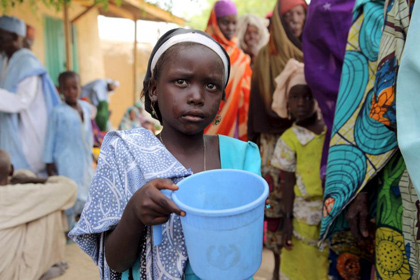 A girl drinks water as women queue for blankets and food given out by Nigerien soldiers in Damasak, March 24. / Reuters.
