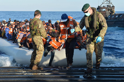 naval personnel rescue migrants from an inflatable craft in the Mediterranean Sea between Italy and Libya . / AP