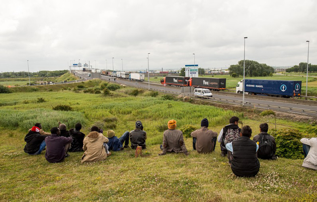 A group of people wait close to the road that leads to Eurotunnel. / Agencies,eurotunnel, july, migrants