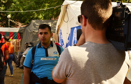 : A volunteer translator being interviewed by a Belgian reporter. The media have general been supportive of the camp. / J. Philippe