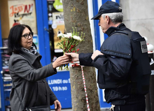 A woman gives flowers to a police man in Rue de Charonne. / AFP,Paris, citizens, attacks, terrorism