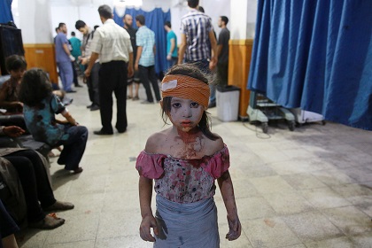 A wounded Syrian girl holds on to a relative as she awaits treatment by doctors at a makeshift hospital in Douma, Syria, 11 May 2015. / Abd Doumany, Syria.