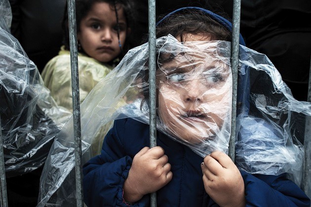 A child is covered with a raincoat while she waits in line to register at a refugee camp in Preševo, Serbia, 07 October 2015. / Matic Zorman,matic zorman, refugees, camps, trauma, children, 2016