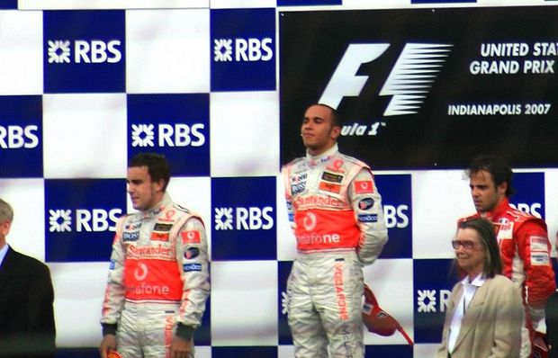 Hamilton on the top podium position after winning the 2007 United States Grand Prix. He is flanked by team-mate Fernando Alonso (left) and Felipe Massa (right).,