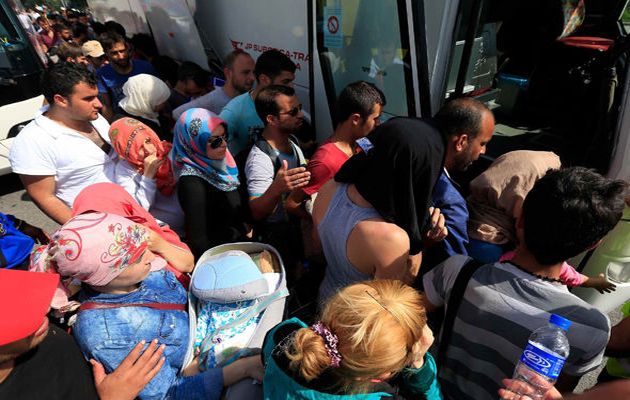 A group of asylum seekers boards a bus start trip to Hungary. / Reuters,