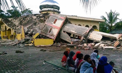 Residents gather outside a damaged mosque, its minaret reduced to rubble following its collapse, after a 6.5-magnitude earthquake struck the town of Pidie. / AFP, Getty