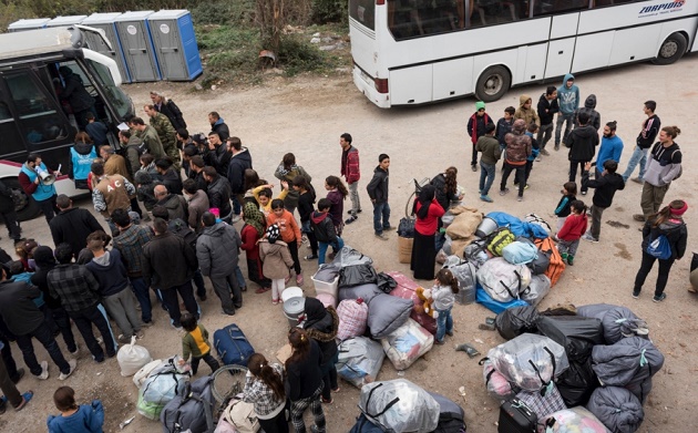 Families in Greece waiting their turn to board a bus transferring them from tented site to apartments. / UNHCR,