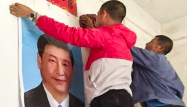 Men put up a poster of Chinese President Xi Jinping in a home in Yugan. / Lvv2.com, South China Morning Post,