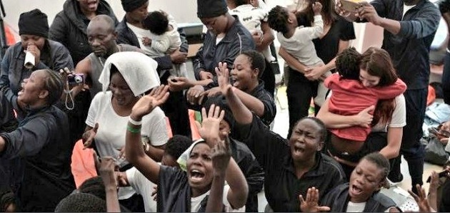 People on board of the Aquarius raise their hands in prayer as they arrive in Valencia, after 8 days. / Levante,