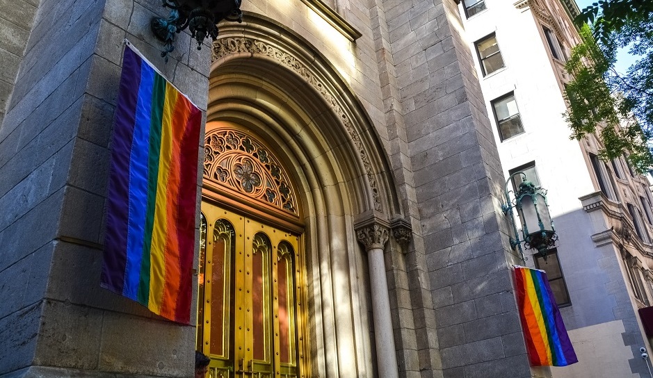 A curch building in New York with LGBT flags. / Photo: <a target="_blank" href="https://unsplash.com/@jeremy0"></a>, Unsplash, CC0.,