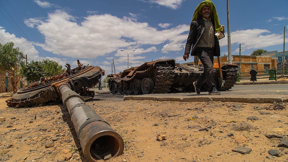 A man walks by a destroyed tank on the main street of Edaga Hamus, Tigray region / <a target="_blank" href="https://commons.wikimedia.org/wiki/File:VOA_Tigray_Children2.jpg">Yan Boechat, VOA, Wikimedia Commons</a>.,