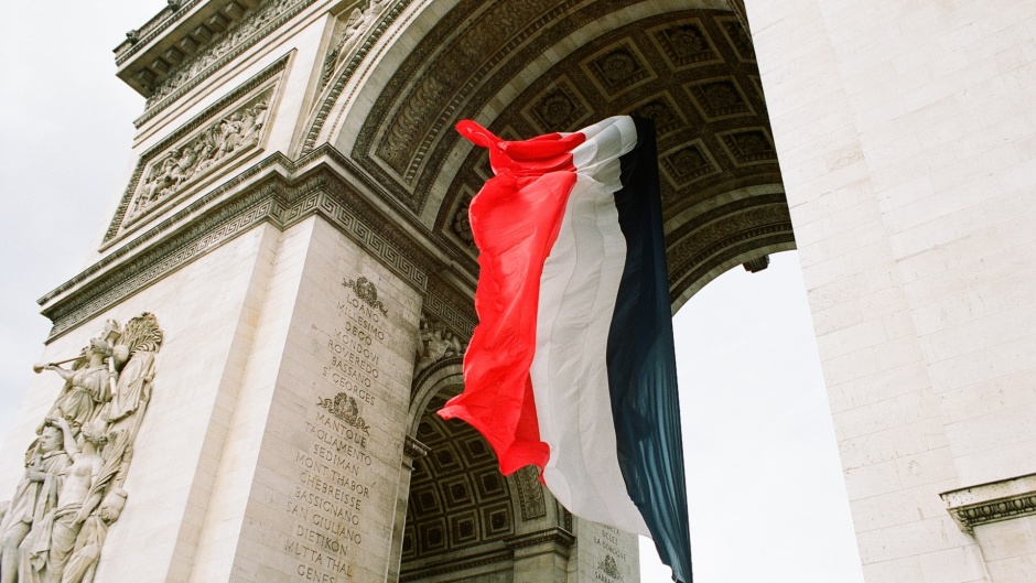 A French flag hanging from the Arc de Triomphe in Paris, France. / Photo: <a target="_blank" href="https://unsplash.com/@me4short">Linda H.</a>,