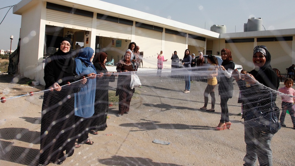 A group of Syrian refugee women in Lebanon, showing a home-made net. / UK DFID, Wikimedia Commons.,